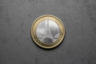 Pièce de 2 euros commémorative Jeux Olympiques 2026 avec la Tour Eiffel, vue de dessus sur fond en béton sombre